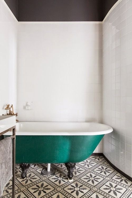 black and white mosaic tiles and a bold emerald clawfoot bathtub make up an eye-catchy bathroom