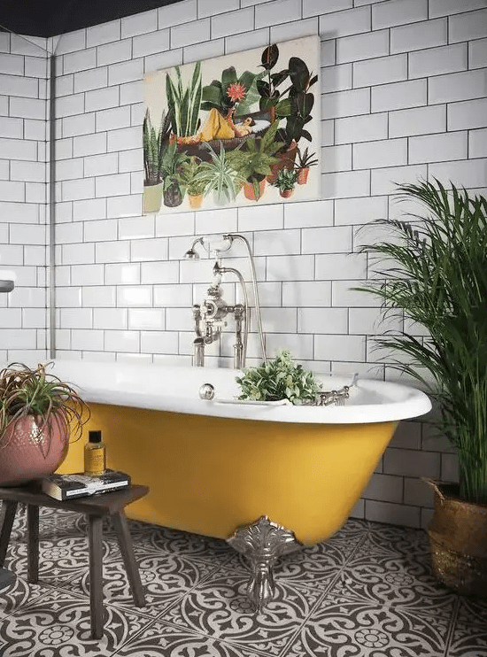 a black and white tile floor, white subway tiles on the walls, a mustard clawfoot bathtub and potted plants plus a bold print