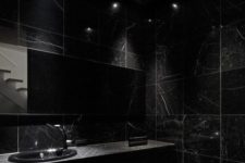a chic black bathroom with blakc marble tiles and a blakc marble vanity plus a black toilet