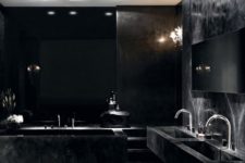 a luxurious all-black bathroom with a marle tub and sinksand touches of shiny metal