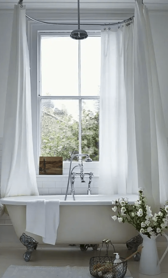 a neutral Provence-inspired bathroom with an ivory bathtub on metall legs and a shower over it
