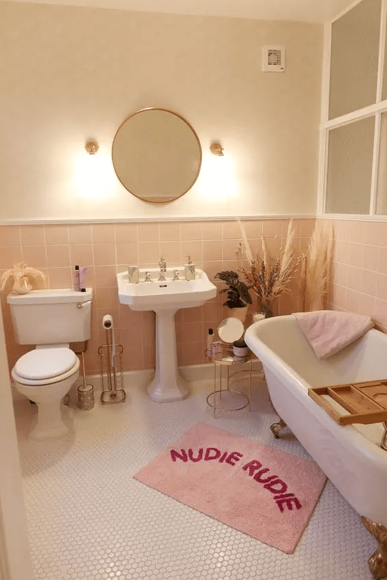 A neutral and blush bathroom with white vintage style appliances, pink textiles and some pampas grass
