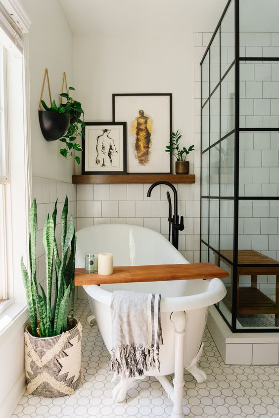 a pretty eclectic bathroom with a shower space, a clawfoot tub, potted greeneyr, some art and black fixtures