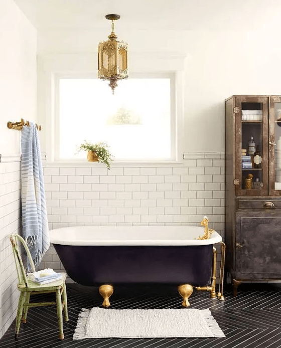 a whimsical bathroom with a black clawfoot tub and gold accents that give the space an exquisite feel