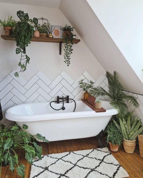 An attic bathroom with a clawfoot tub, herringbone tiles, lots of greenery feels very cool and boho  like