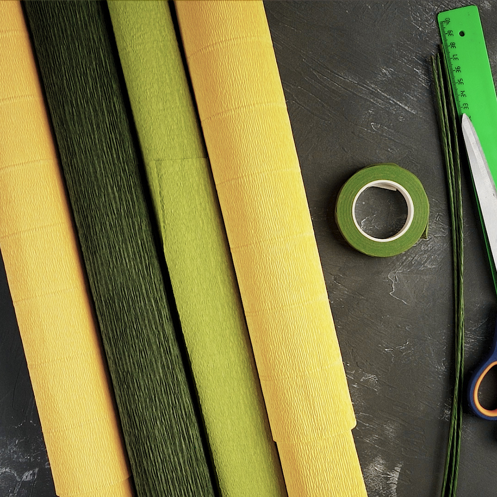 The supplies are a ruler, scissors, florist wire, masking tape in green, crepe paper in several shades of green and yellow.