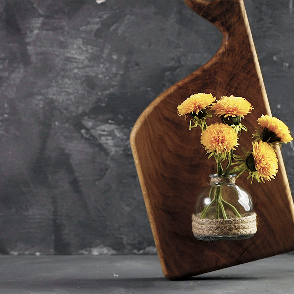 If you have an old chopping board, hot glue your vase to it and hang it on the wall.