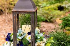 12 a vintage lantern filled with moss balls and with fake blooms and greenery won’t wither fast