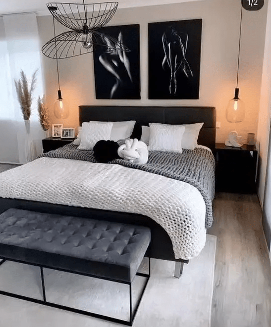 a chic and dramatic bedroom with a black bed and monochromatic bedding, a black upholstered bench, black nightstands and a chandelier