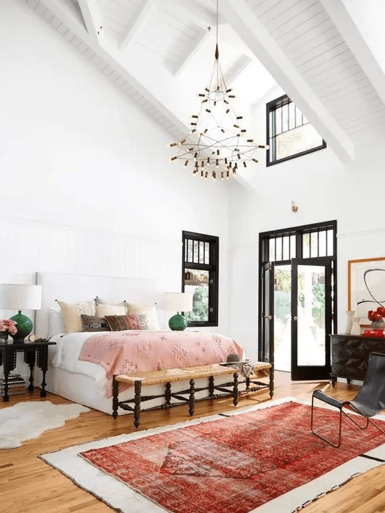 an attic eclectic bedroom with a white bed and some bright bedding, mismatching nighstands and lamps, a bold rug and a black dresser