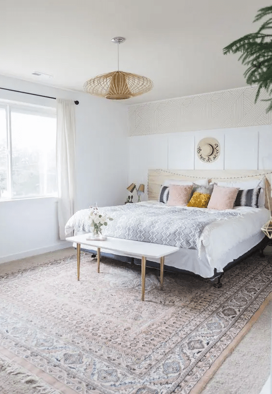 an eclectic bedroom with white paneling, a bed with printed bedding, a printed rug, a pendant lamp and greenery