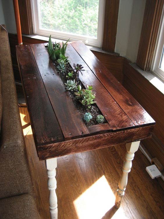 a stained pallet side table with a planter in the center and lots of succulents growing is a fresh rustic idea