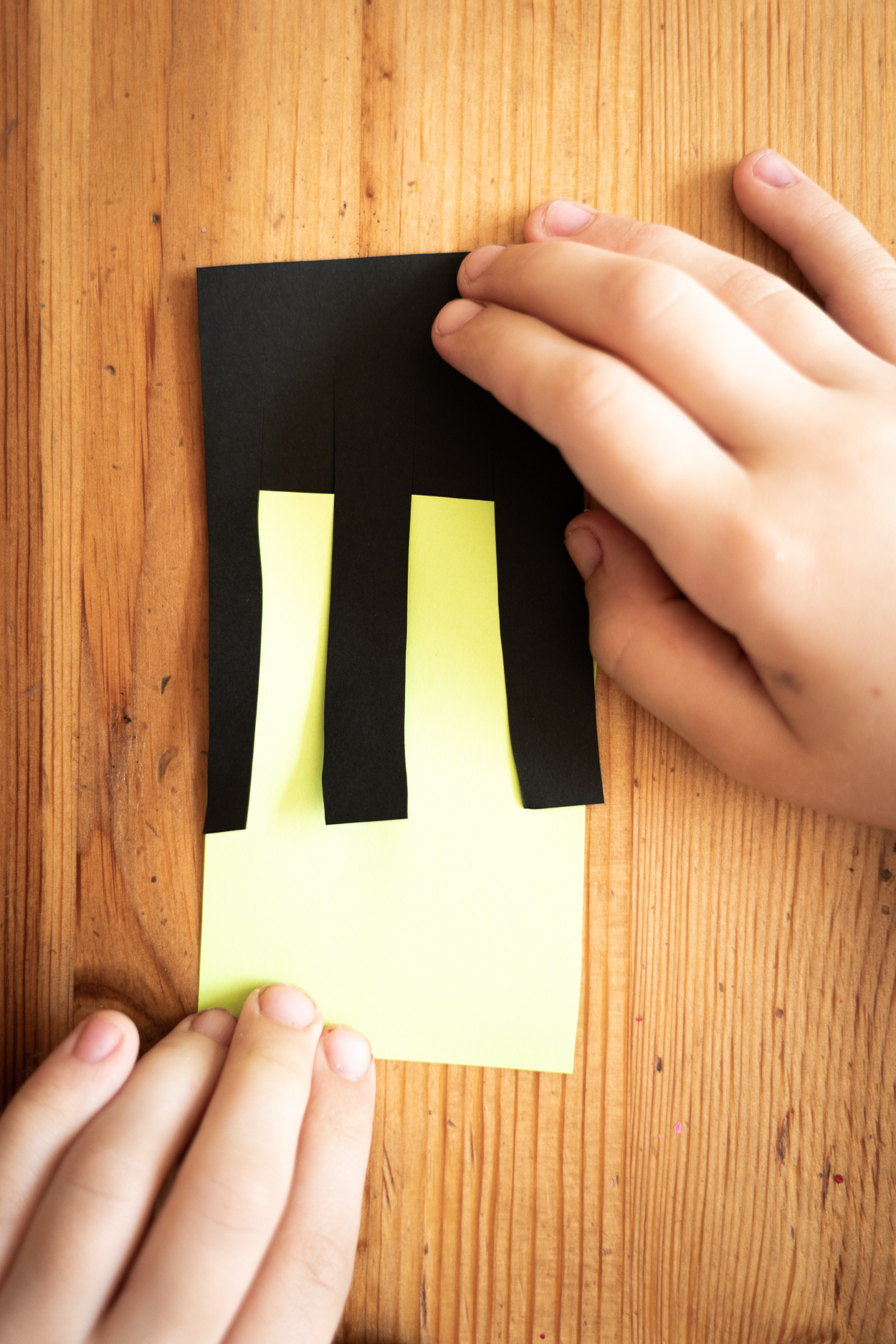 Cut out a rectangle of black paper and put it on a sheet of neon green paper, trace it with a pencil, cut out the rectangle. Take a black rectangle and cut long fringe in it, then put this piece of paper on your bright neon rectangle. Glue the black fringe to the neon rectangle on both sides.