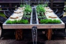 15 an outdoor dining table with planters with fresh greenery and herbs for eating and a waterfall will be a statement in your garden