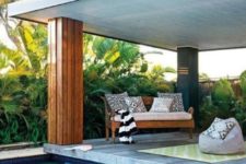03 a contemporary pool cabana with a wooden bench, a bean bag chair, a colorful rug and lots of greenery