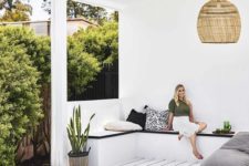 05 a contemporary tropical pool cabana in white, with black surfaces, a wicker lamp and potted plants