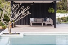 07 a minimalist black pool cabana with striped pillows on a single upholstered sofa for those who dont’ like anything excessive