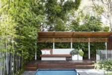 09 a modern farmhouse cabana with potted plants, a stained wooden bench and a large deck by the pool