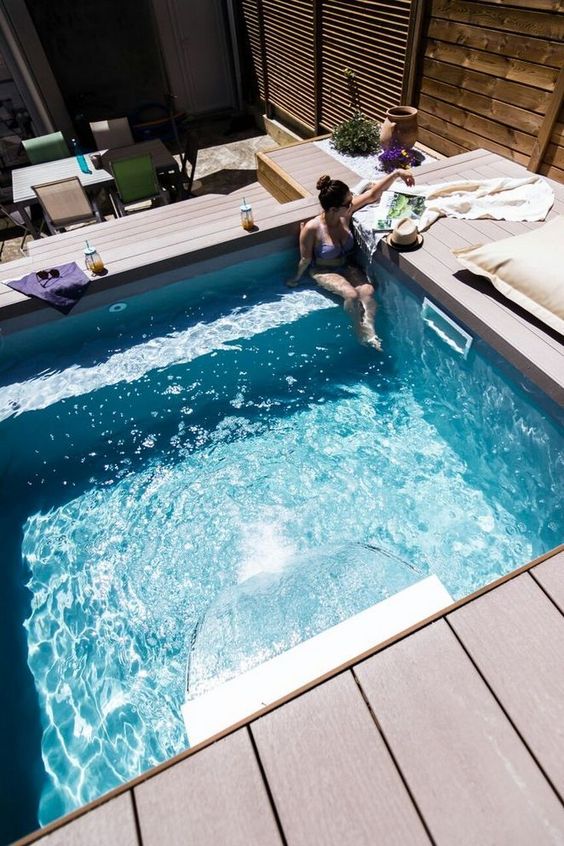 a gorgeous contemporary wooden deck with several levels and a small bakcyard pool with a built-in bench