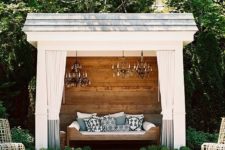 15 a small rustic pool cabana with a single wooden bench with pillows, elegant crystal chandeliers, plants around and curtains