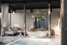 23 a luxurious pool cabana with an outdoor tub, some upholstered furniture, a round mirror and console plus a pool to create an ultimate oasis