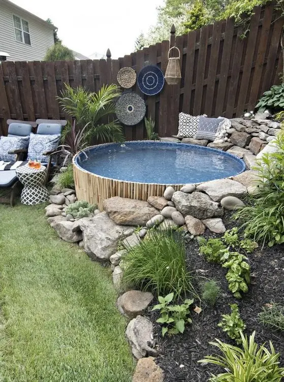 a boho outdoor space with planted greenery, boho decor, printed blue textiles and a small round pool clad with bamboo