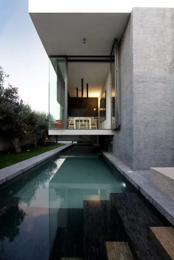 a contemporary outdoor space with a long narrow pool with built-in lights and a balcony over the pool to jump in immediately