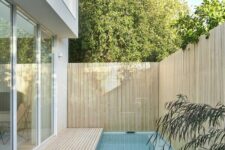 a contemporary outdoor space with a woodne deck and a small and narrow pool plus a wood slat fence around