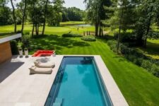 a contemporary outdoor space with an infinity pool, neutral stone tiles, soft loungers and a fire pit done in fiery red
