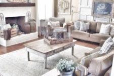 a cozy and neutral farmhouse living room with upholstered furniture, a shabby chic coffee table, a neutral fireplace and vintage doors for decor