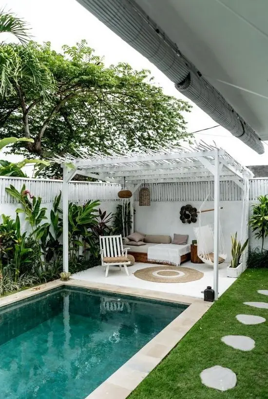 a cozy boho chic cabana done in white and neutrals and a small swimming pool clad with neutral tiles