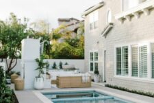 a gorgeous neutral backyard with a pool with a hot tub, a stone deck, some lovely outdoor furniture and potted greenery