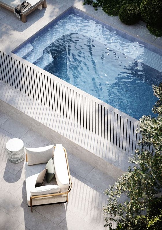 a minimalist outdoor space with a plunge pool clad in stone, loungers and chairs is a very lovely nook to have a rest in