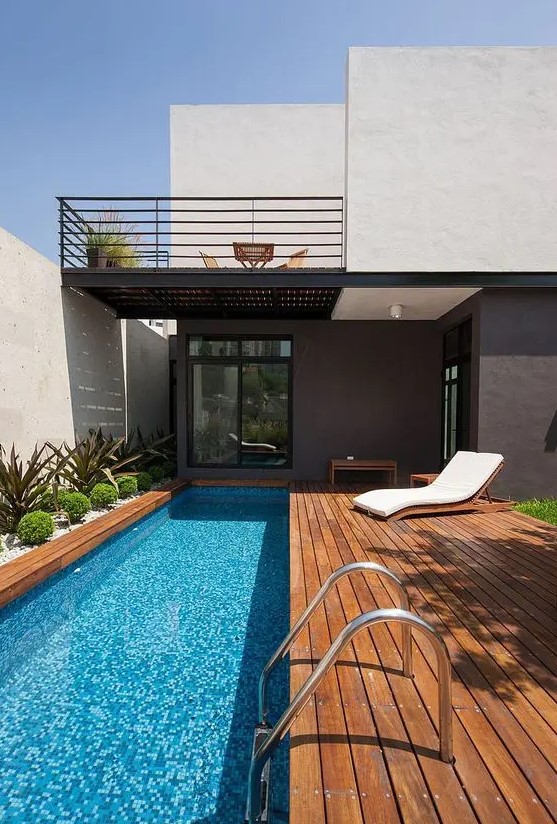 a modern wooden deck with a narrow pool and desert plants lining it up is a cool solution for a minimal or modern backyard