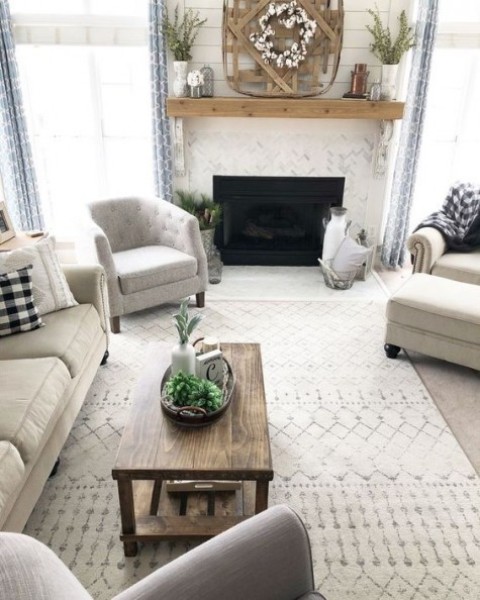 a neutral living room with comfy furniture, a wooden coffee table, a fireplace with a wooden mantel and some arrangements