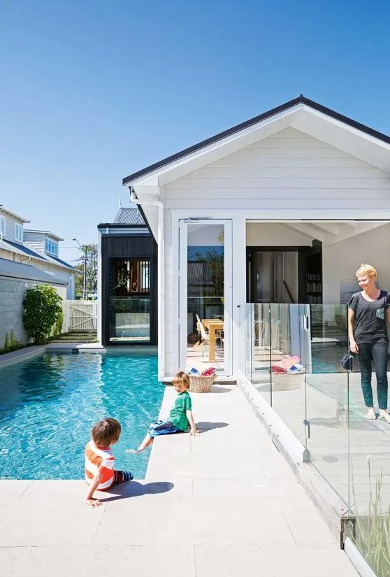 a pretty modern backyard with a stone deck, a small pool, a glass fence to make the zone safe