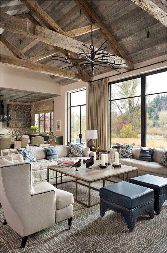 a rustic farmhouse living room with much light-colored wood,cremay furniture, a branch chandelier and printed pillows