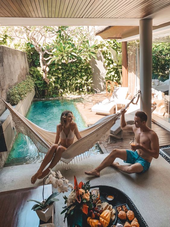a small backyard pool surrounded with greenery, a with a wooden deck with loungers and a hammock is a perfect boho retreat