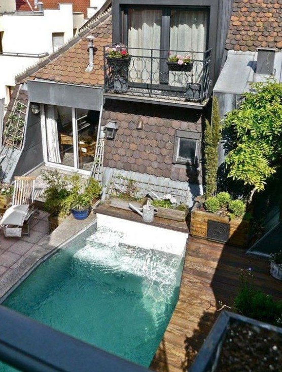 a small yet cool outdoor space with a wooden and tile deck, a plunge pool, some greenery and potted greenery is welcoming