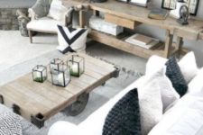 a stylish farmhouse living space with rough wooden tables, white upholstery, some prints and a faux stone clad fireplace
