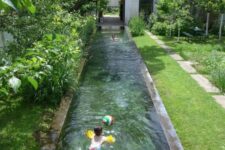 a super lush and green garden featuring a long and narrow pool that looks absolutely natural here and is surrounded with greenery