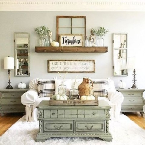 a vintage farmhouse living room with a green vintage chest as a coffee table, a white sofa with checked pillows, a wooden shelf and mirror window decor
