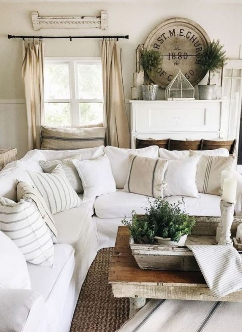 a vintage farmhouse living room with upholstered neutral furniture, neutral curtains, vintage decor and potted greenery