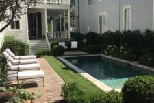 an elegant backyard with a pool clad with stone, with a green lawn, some loungers and a brick deck is an adorable space to have a rest