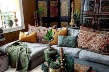 a Moroccan boho liivng room with a sectional sofa, printed pillows and rugs, a large Moroccan lantern, a wooden screen and a carved table