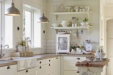 a beautiful white farmhouse kitchen with butcherblok countertops, pendant lamps and a white subway tile backsplash