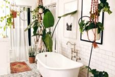 a boho bathroom with lots of potted greenery hanging nd standing, boho rugs and a mosaic tile floor