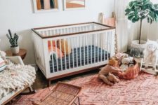 a boho nursery with a bright red rug, boho hangings, mid-century modern artworks and fluffy touches