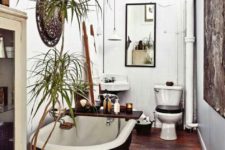 a boho rug on the wall, potted plants, a mirror, a rich stained wooden caddy with various bathroom stuff and candles