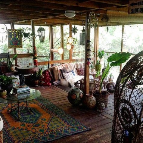 a boho screened porch, rattan and wooden furniture, lanterns, potted greenery, boho textiles and artworks